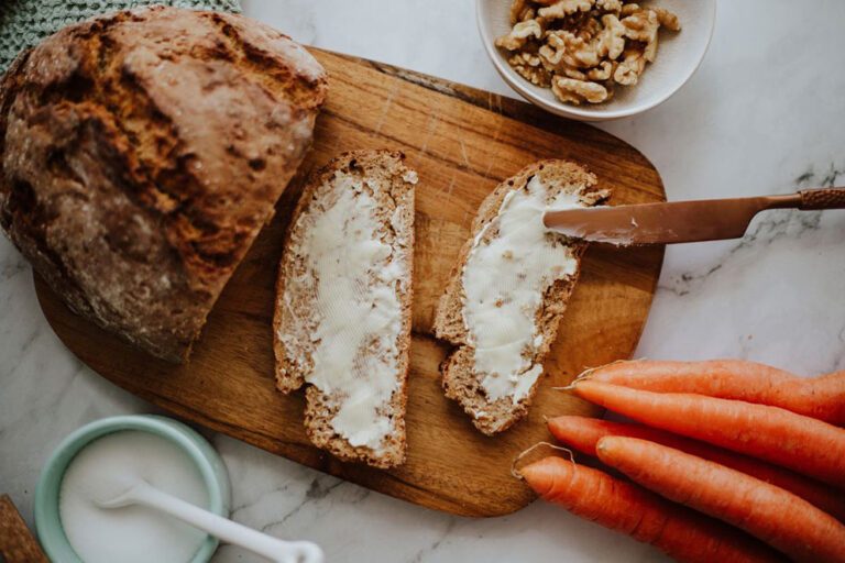 Selbst gemachtes Karottenbrot liegt mit Butter bestrichen auf einem Holzbrett.