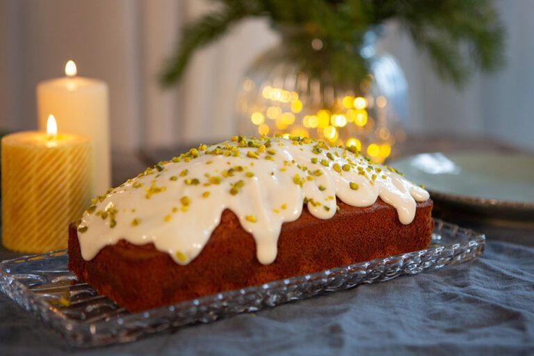 Der Chai-Honigkuchen mit dem Frischkäse-Frosting steht auf einem gedeckten Tisch.